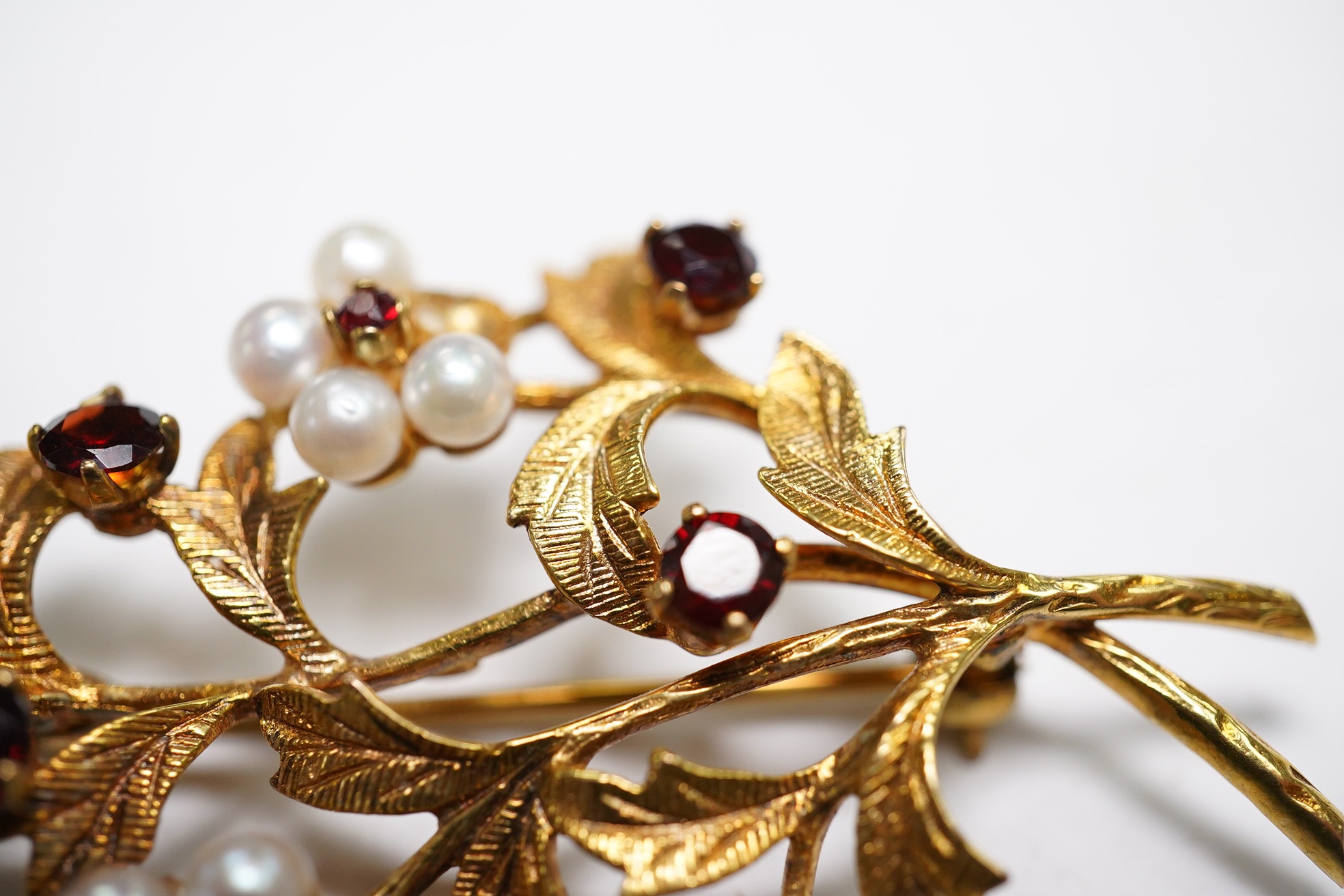 A 1960's 9ct gold, cultured pearl and garnet cluster set foliate spray brooch, 52mm (three pearls missing), gross weight 9.3 grams. Condition - poor